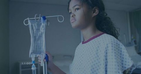 Brave child patient holding iv bag in hospital room