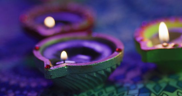Lit candles in decorative clay pots on patterned table top, focus on foreground, bokeh background. diwali festival, celebration, tradition and ceremony concept.