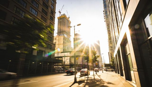 Sunburst over busy downtown street at golden hour with construction crane and traffic