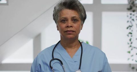 Senior Nurse Standing Wearing Light Blue Scrubs and Stethoscope Exuding Calm Authority