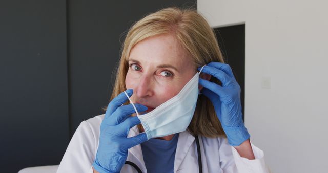 Female Doctor Wearing Blue Gloves Adjusts Face Mask in Hospital - Download Free Stock Images Pikwizard.com