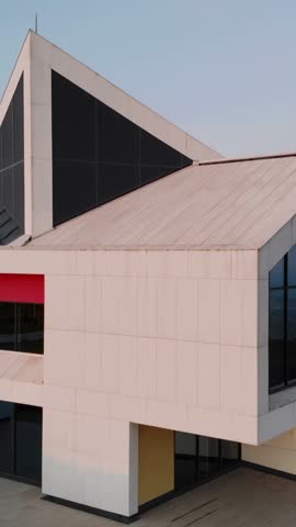 Vertical pan revealing modern commercial building with triangular roof and glass wall