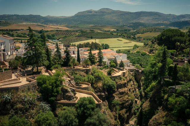 This stock image depicts a picturesque Spanish village situated on the edge of a gorge, offering a stunning panoramic view of the surrounding countryside and mountains. The lush greenery and the charming architecture make it a perfect fit for travel brochures, cultural presentations, and nature-themed projects.