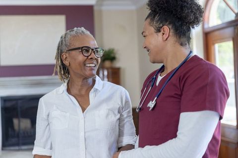 Senior african american woman receiving compassionate homecare visit from nurse