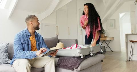 Couple Packing Luggage for Trip with Tablet at Home