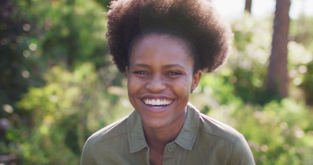 Portrait of smiling african american woman standing in sunny garden. staying at home in isolation during quarantine lockdown.