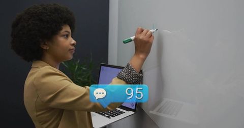 Businesswoman writing on whiteboard holding laptop presenting with chat notification