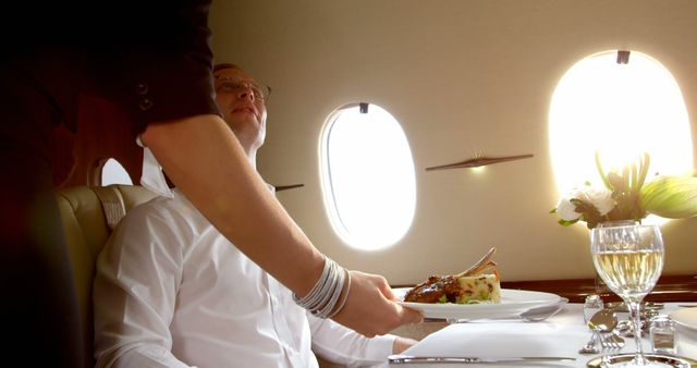 Man dining luxury meal in private jet served by flight attendant - Download Free Stock Images Pikwizard.com