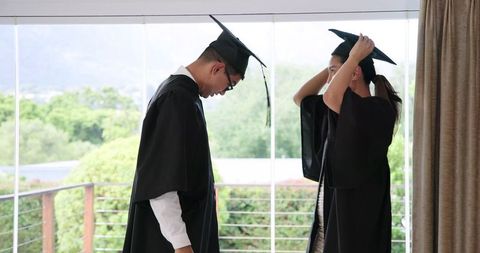 Graduating Couple Adjusting Caps in Terrace Setting