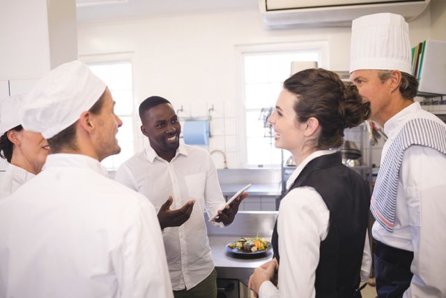 Restaurant manager briefing kitchen staff in a commercial kitchen. Ideal for illustrating teamwork, communication, and leadership in the hospitality industry. Useful for articles on restaurant management, culinary training, and professional kitchen environments.