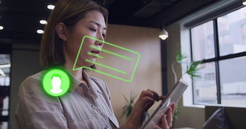 Asian woman tapping tablet in modern co-working space with augmented reality messaging overlay
