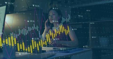 Chinese analyst monitoring market charts on laptop at night while taking phone call