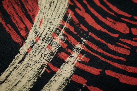 Bold red and ivory brushstroke textile featuring distressed black woven texture