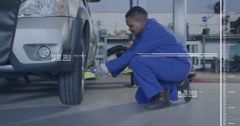 Automotive technician changing suv wheel using impact wrench in busy workshop garage