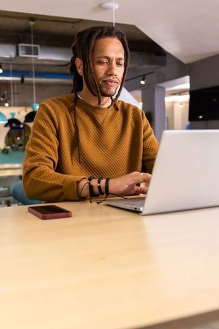 African american man working on laptop in modern coworkorking space, remote professional focus