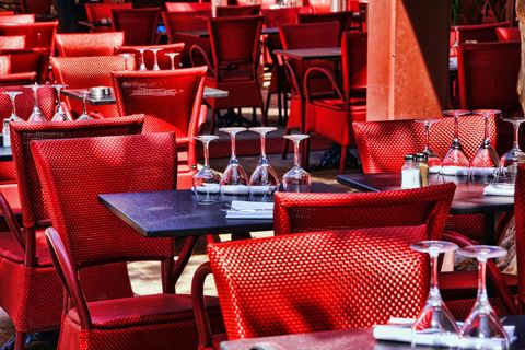 Sunlit red bistro chairs and tables with inverted wine glasses at outdoor cafe