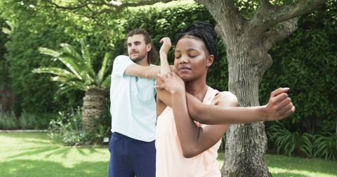 Diverse Duo Stretching in Garden for Outdoor Yoga Session