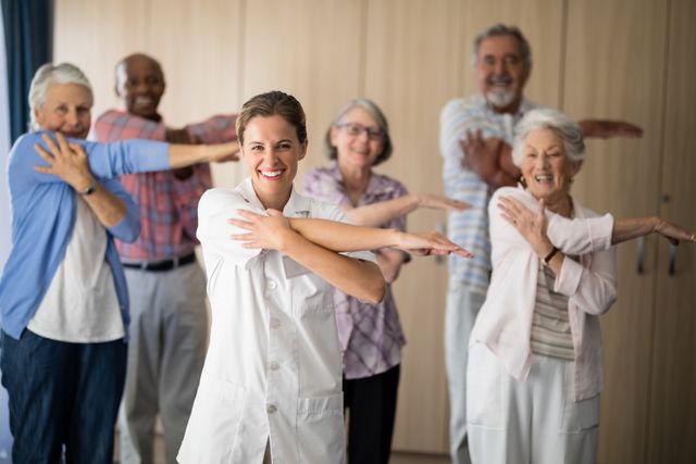 Portrait of smiling female doctor and seniors stretching arm against wall at retirement home