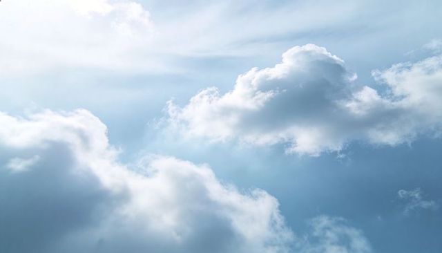 Drifting Cumulus Clouds with Sunbeams and Layered Light over Expansive Blue Sky