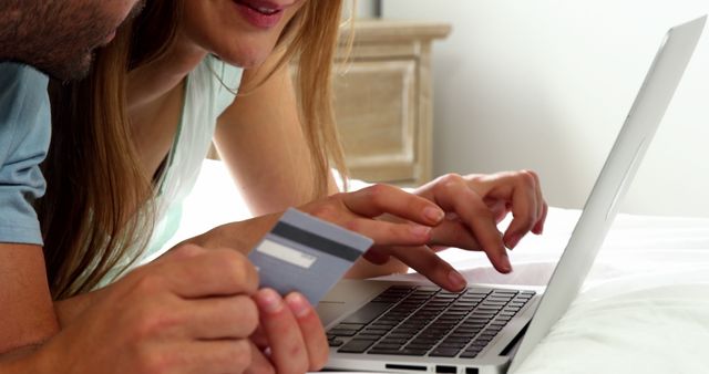 A young Caucasian couple is engaged in online shopping or banking on a laptop, with copy space. They appear to be entering payment information, highlighting the convenience and intimacy of modern digital transactions.