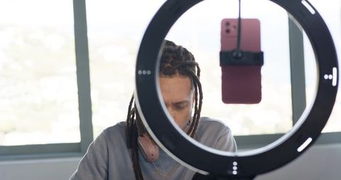 African american creator streaming with ring light and mounted smartphone