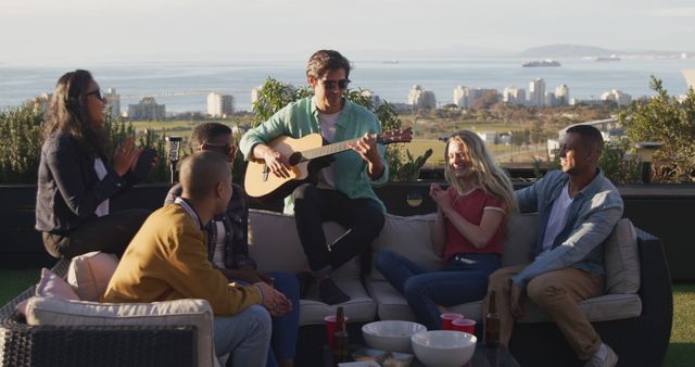 Friends enjoying outdoor gathering with a guitar on rooftop - Download Free Stock Images Pikwizard.com