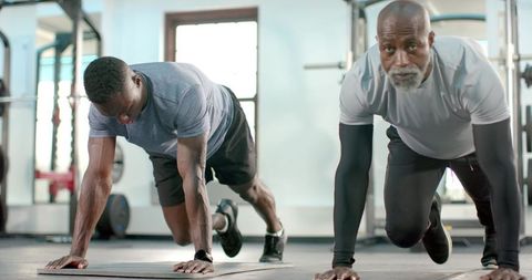 African american men doing mountain climbers on mats in gym building strength and endurance