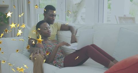 Couple relaxing on sofa cuddling and typing on laptop with golden star overlays cozy home lifestyle