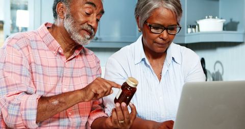 Senior Couple Checking Medicine Loan Labs Online in Kitchen