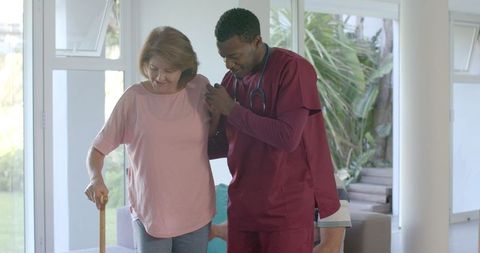 Caregiver assisting senior woman in rehabilitation exercise at home