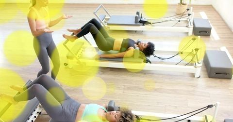 Pilates instructor guiding women through reformer bridge exercises in sunlit studio class
