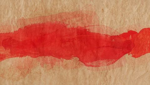 Red paint wash sweeping across kraft paper texture showing brush strokes and drips