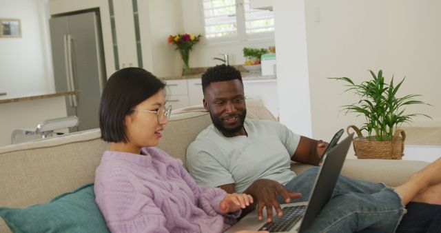 Diverse Couple Relaxing on Sofa Using Laptop and Smartphone - Download Free Stock Images Pikwizard.com