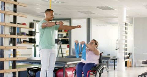 Therapist assisting with resistance bands for wheelchair rehabilitation