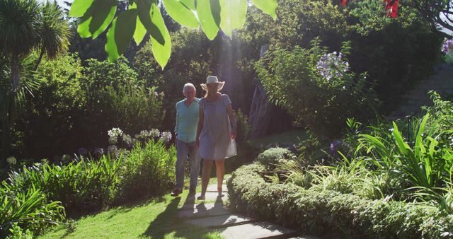 Caucasian senior couple walking in garden together in the sun. staying at home in isolation during quarantine lockdown.