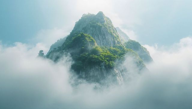 Majestic mountain peak emerging through misty clouds