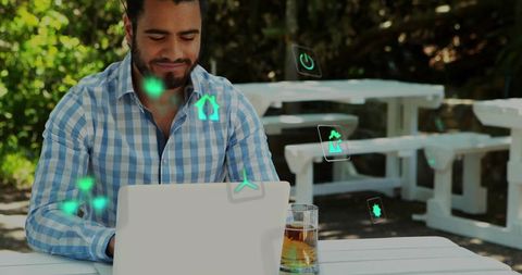 Outdoor remote work man using laptop at park table with holographic smart home icons