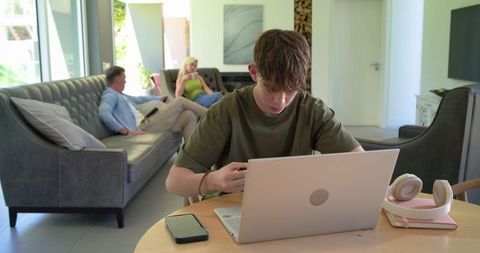 African family modern living room teenager studying on laptop parents relaxing near sofa