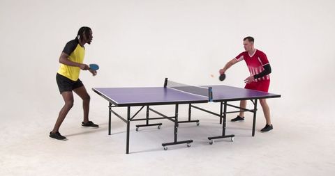 Diverse male players enthusiastically competing in table tennis match