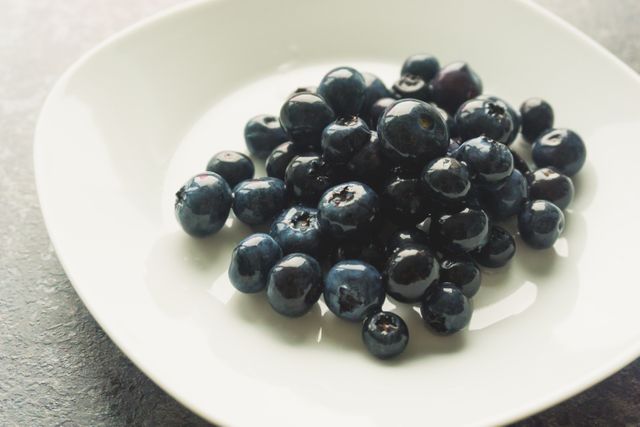 Close-up of plump, juicy blueberries in a white bowl. Ideal for promoting healthy eating, fresh produce, and antioxidant-rich diets. Perfect for use in recipes, food blogs, and health-related content.