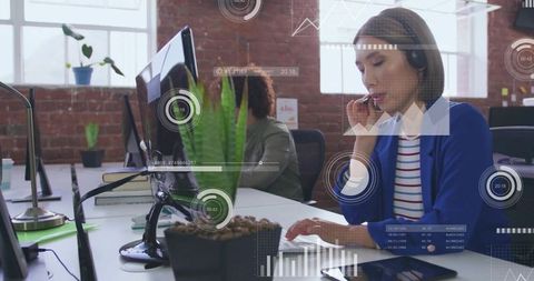 Customer Support Agent Talking on Headset While Typing at Modern Open-Plan Office Desk