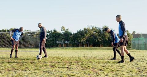 Soccer Coach Training Young Players Outdoors on Football Field