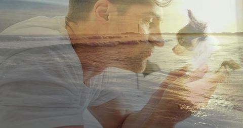 Man cradling small longhaired dog with ocean sunset overlay, intimate golden hour moment