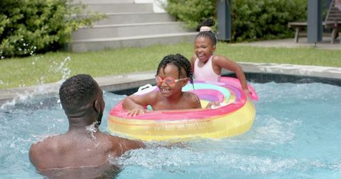 Joyful family pool time: siblings splashing with father