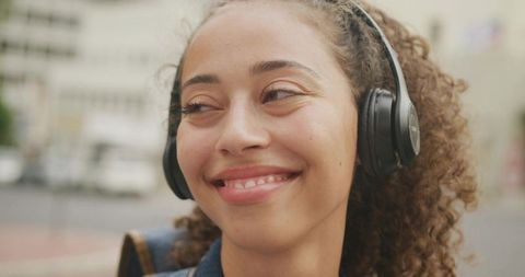 Joyful Young Woman Enjoying Music with Headphones Outdoors