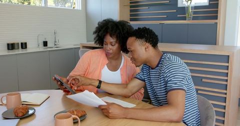 Young Couple Reviewing Financial Documents at Home Table Setup