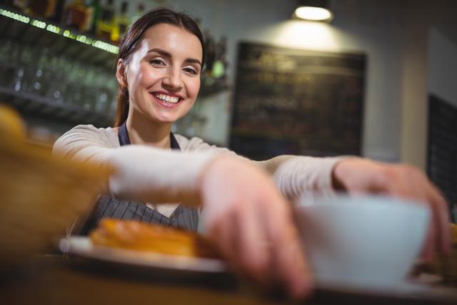 Portrait of waitress serving a cup of coffee to customer in cafÃ©