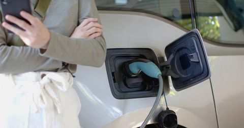 Woman Charging Electric Car at Home using Smartphone Technology