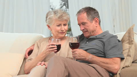 Senior Couple Relaxing with Red Wine at Home