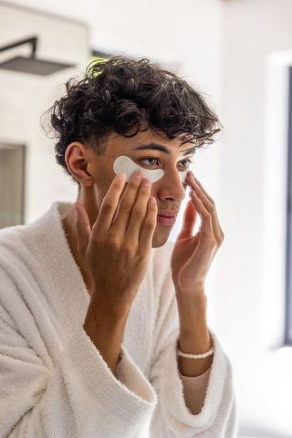 Man applying under-eye gel patches for skincare routine